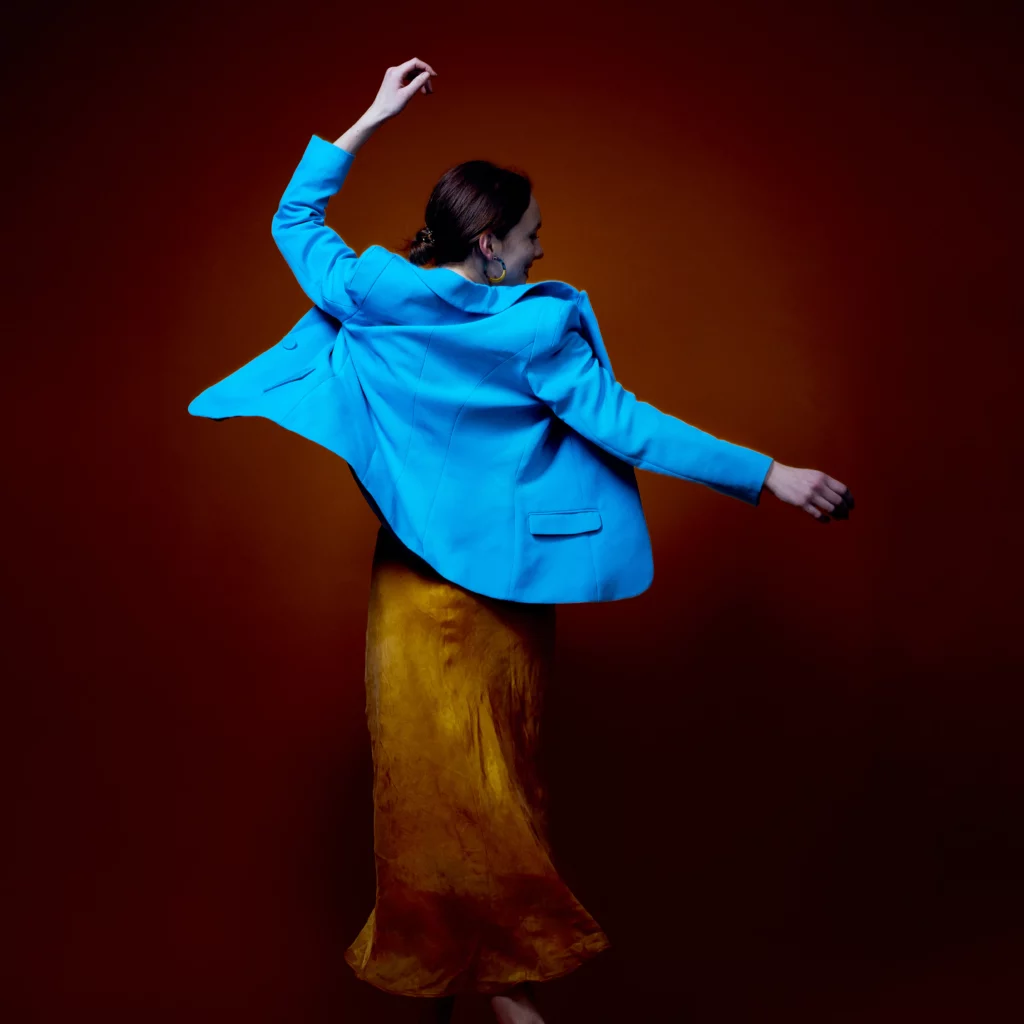 Fotoaufnahme einer tanzenden junge Frau mit blauen Blazer