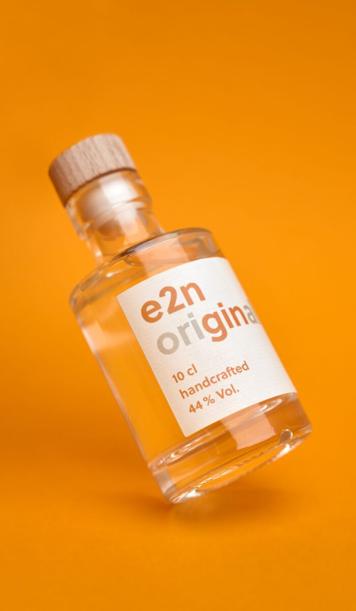 e2n Gin auf orangenem Studiohintergrund in durchsichtiger Ginflasche